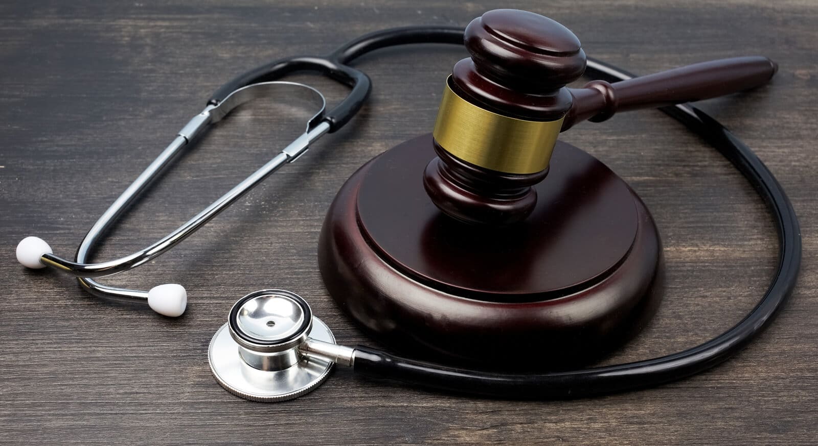Gavel and stethoscope on black wooden background